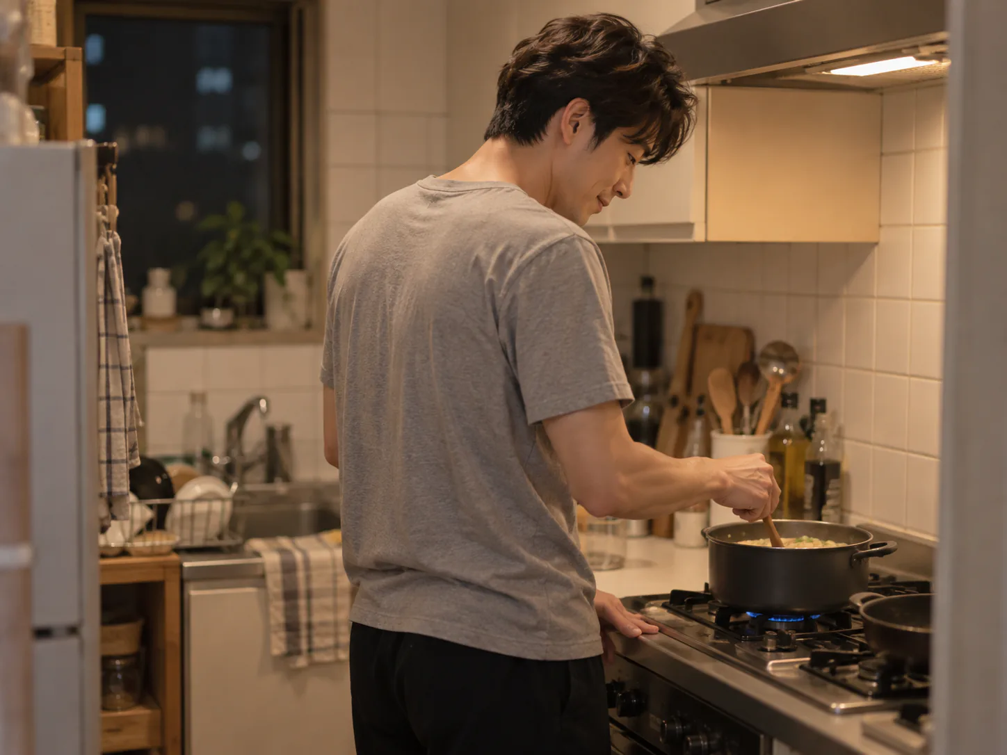 夜のキッチンで、慣れない手つきで鍋をかき混ぜる夫