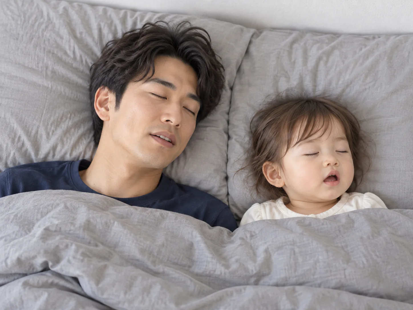 布団で眠る娘の寝顔を、そばで見ている夫