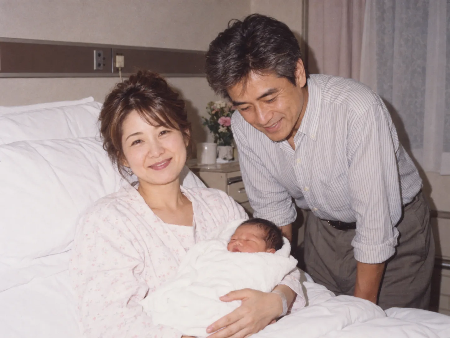 1994年、産院のベッドで生まれたばかりの娘を抱く妻と、のぞき込む誠一