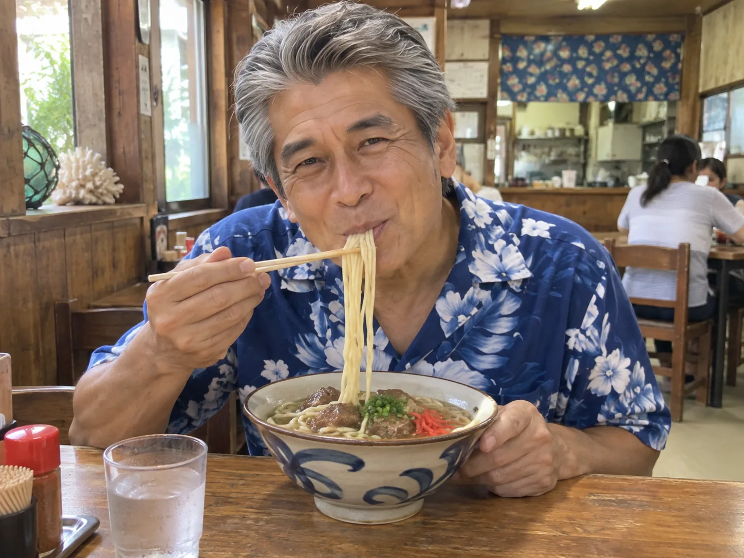 沖縄の食堂で、アロハシャツ姿でソーキそばをすする誠一