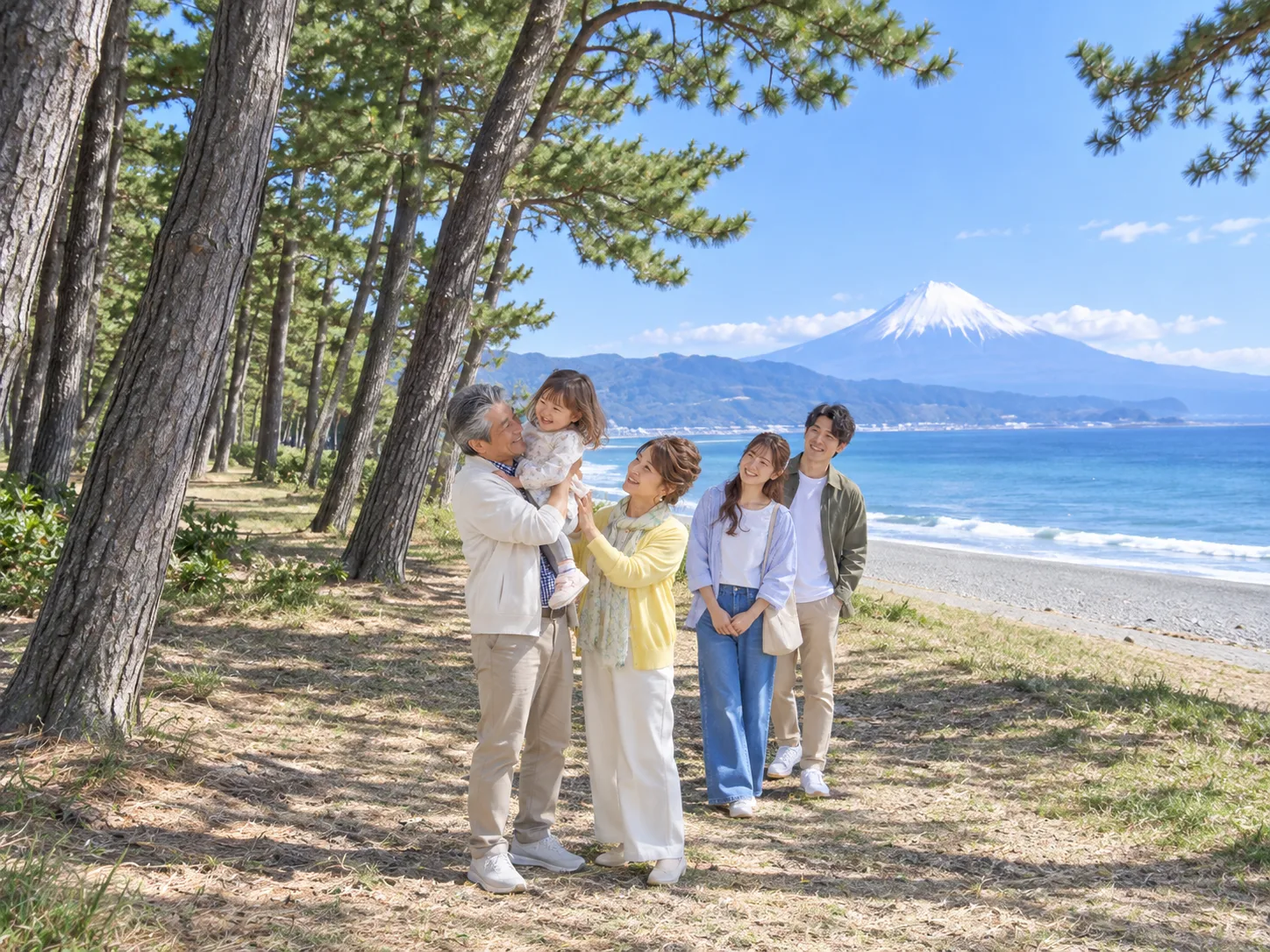 富士山の見える海辺の松林で、孫を抱き上げる誠一と家族