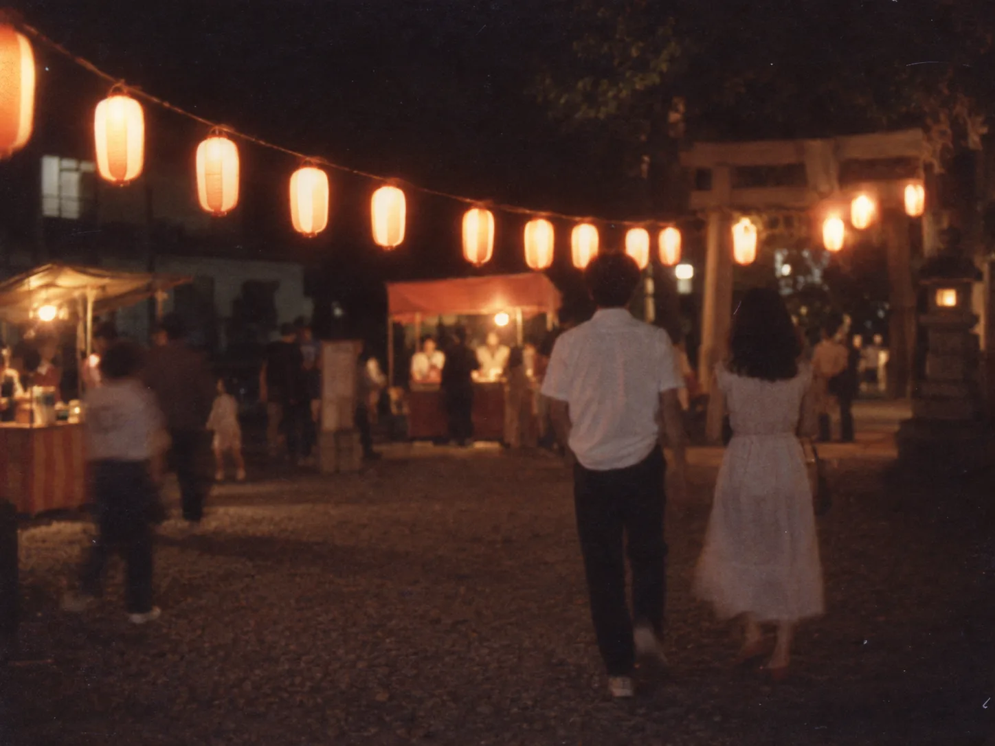 1980年代後半、夏祭りの夜。並んで歩く二人の後ろ姿